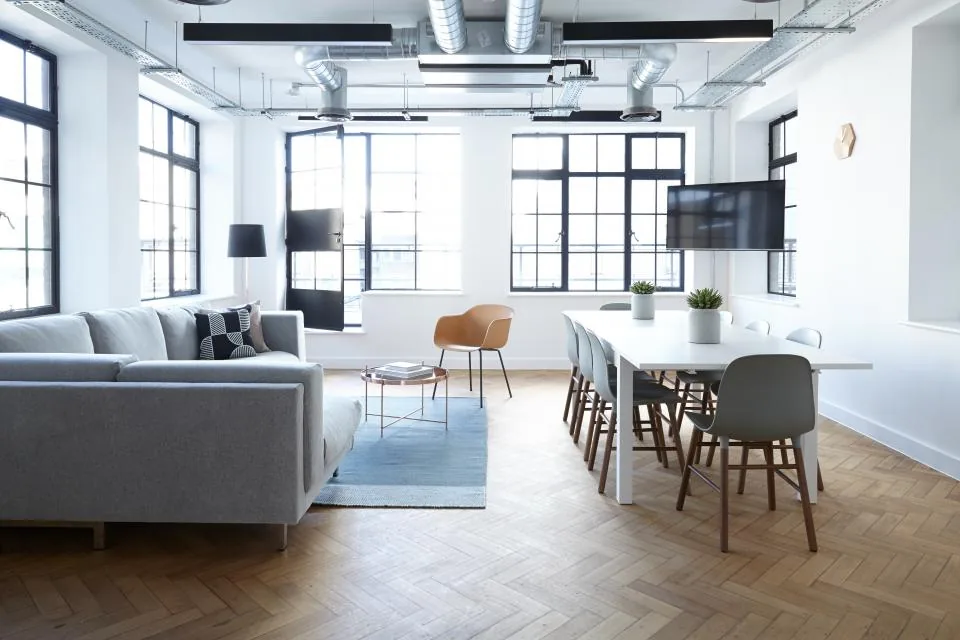 A bright, modern studio office with a lounge area, a meeting table and tall windows